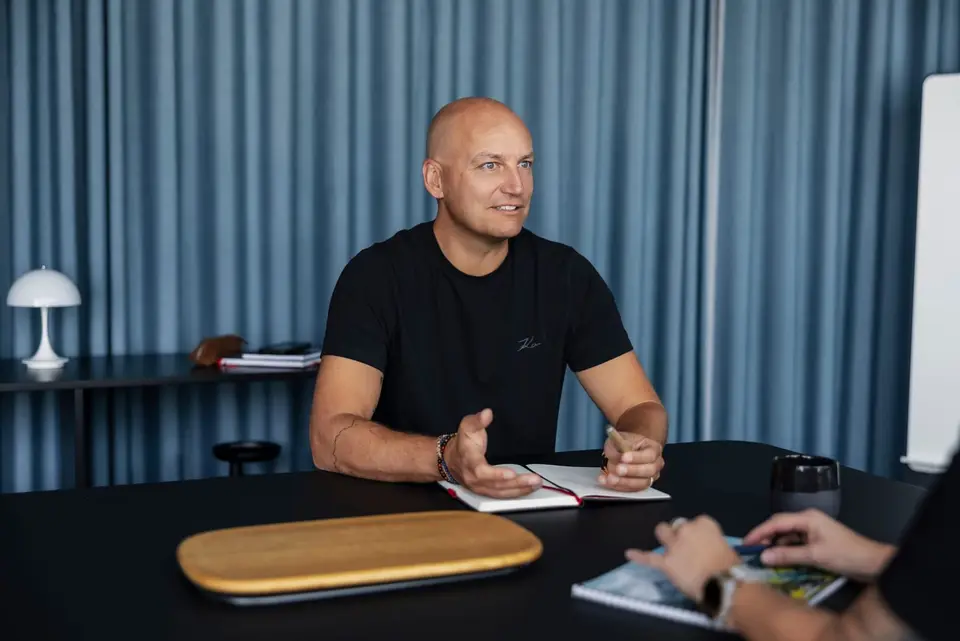 Christian Kirsch im Gespräch — schwarzes T-Shirt, blauer Vorhang im Hintergrund.