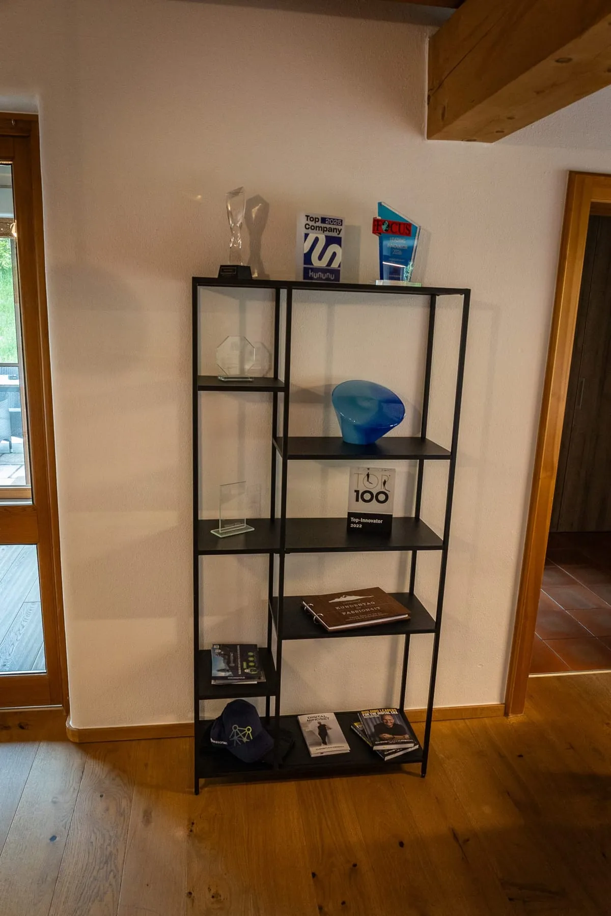Award-Regal im PASSION4IT-Office: Pokale, Innovator-Trophäen, kununu-Top-Company-Schild und FOCUS-Auszeichnung auf einem Stahl-Regal vor heller Wand.